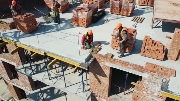 Aerial View Builders Working on Construction and Laying Bricks alt