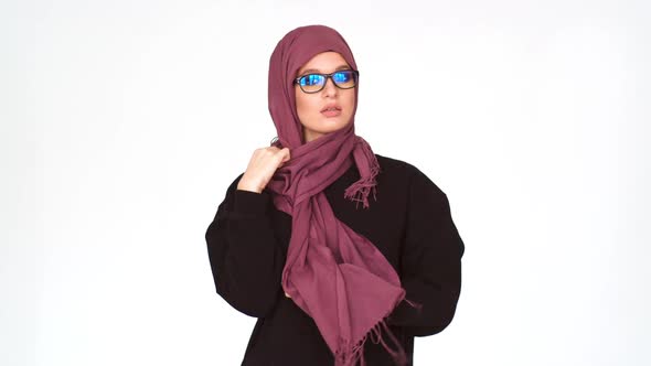 A Muslim Woman Resistance Removes Her Headscarf. A Young Girl Untangles a Muslim Headdress and Looks alt