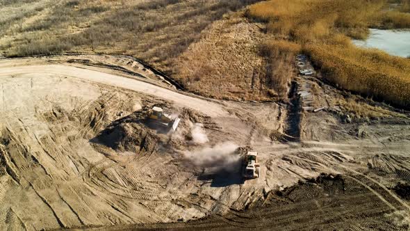 Bulldozersing mounds of dirt on a large construction site - aerial view alt