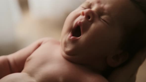 Cinematic video portrait newborn baby yawns, sleepy cute baby child. alt