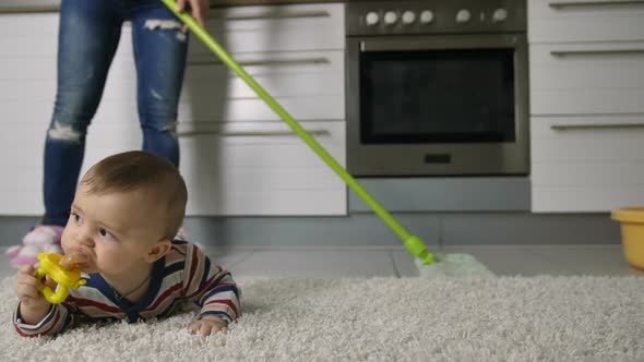 Woman's Legs Cleaning Floor Near Baby alt