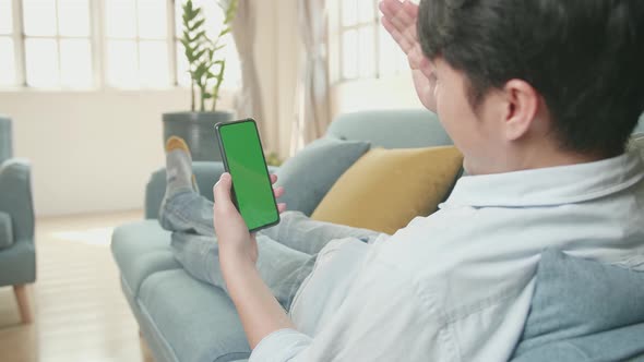 Male Video Call While Using Smartphone With Green Screen Display In Living Room alt