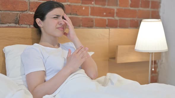 Young Indian Woman Feeling Worried while Sitting in Bed alt