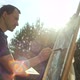 A Male Artist Paints a Picture on an Easel with a Brush - VideoHive Item for Sale