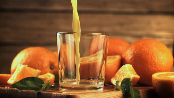 A Stream of Orange Juice Pours Into the Glass alt