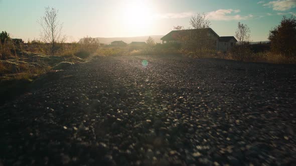 Low angle moving down a gravel road at sunset - animal POV close to the ground alt