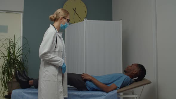 Female Doctor Palpating with Hands Sick Male Patient Abdomen Indoors alt