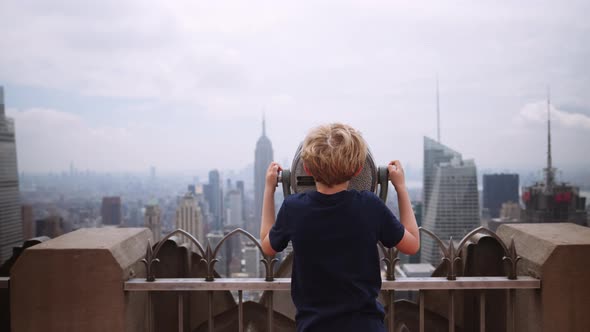 Boy Looking Through Telescope To View New York Skyscrapers alt