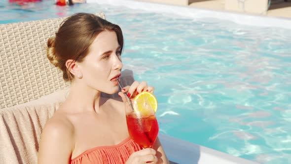 Beautiful Happy Woman Enjoying Drinking Cocktail at the Poolside alt