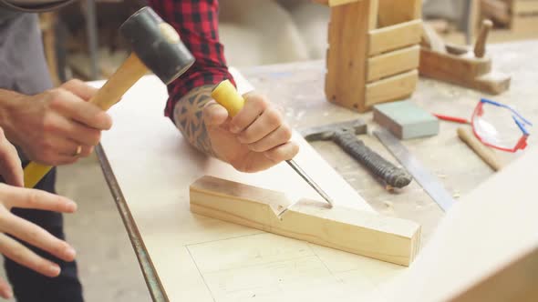 Man in Apron Works with Chisel in a Carpentry Shop alt