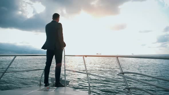 Successful man in a suit sailing on a yacht on the sea to the horizon. 4K shot alt