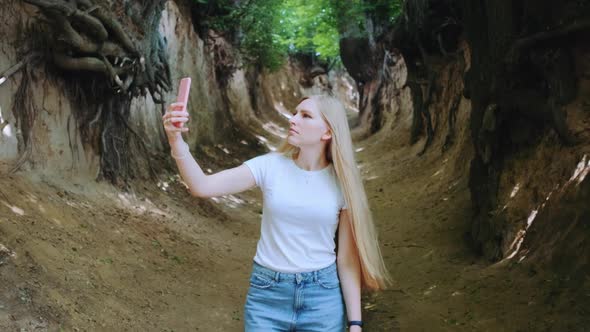 Blonde Young Woman Making Photos on Smartphone in Magical Roots Gorge alt