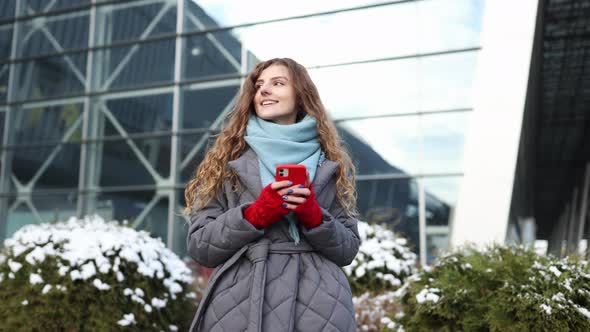 Woman Texting on Smartphone Standing on Street in Winter City on New Year
