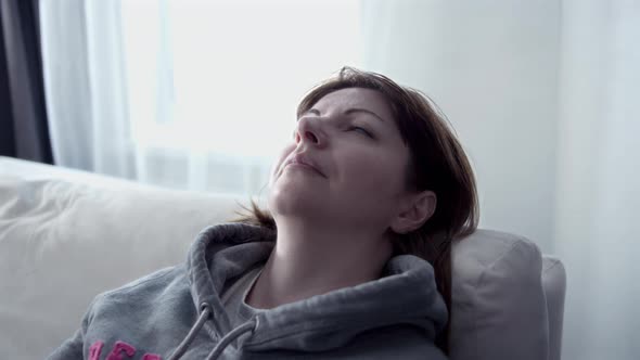 Happy Woman Puts Her Head on the Back of the Sofa and Closes Her Eyes Woman Relaxing at Home