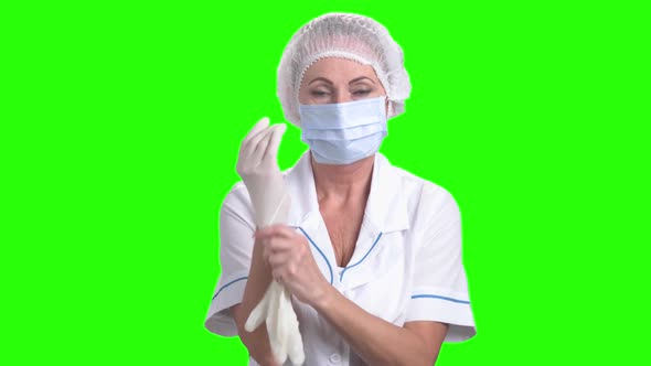 Female Surgeon Putting on Protective Gloves. alt