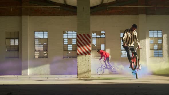 BMX riders in an empty warehouse using smoke grenade alt