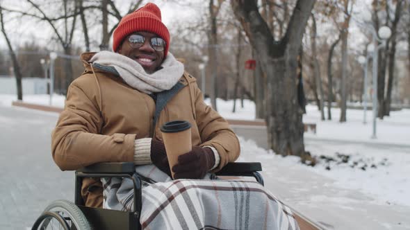 Portrait of Cheerful Black Man on Wheelchair with Coffee Outdoors alt
