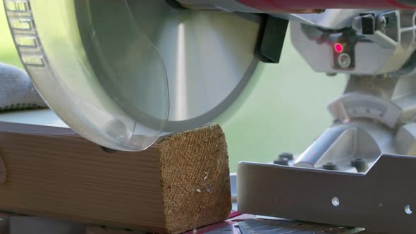 Cutting Off 4X4 Wooden Post on Mitre Saw Close-up. Circular Saw Blade in Motion alt