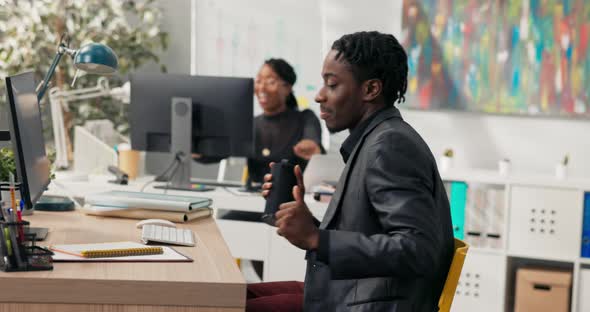 Darkskinned Coworkers Sit in the Company's Office in Front of Computers Dancing Singing Happy About alt