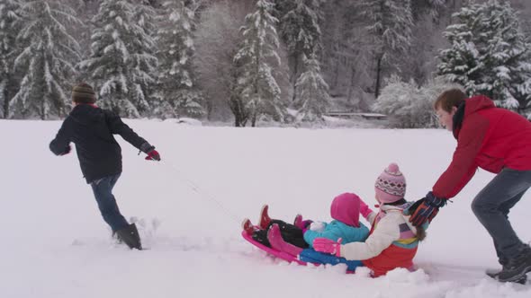 Kids playing and pushing sled in winter snow