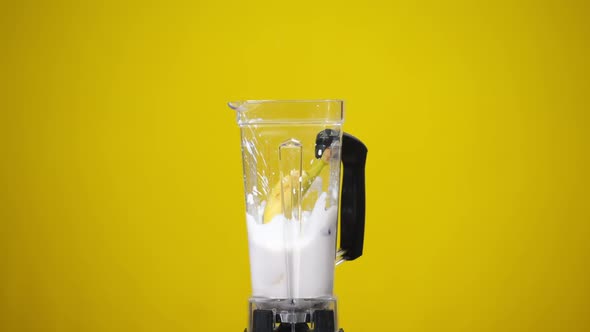 Milkshake with Strawberries at Yellow Background and Whole Banana Falling Inside Splashing Cocktail alt