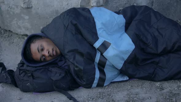 African Male Refugee Lying Street Ground Covered With Sleeping Bag, Homelessness alt