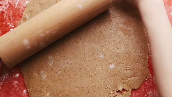 Woman Rolling Out the Dough with a Rolling Pin on a Red Silicone Baking Mat for Gingerbread Cookies alt