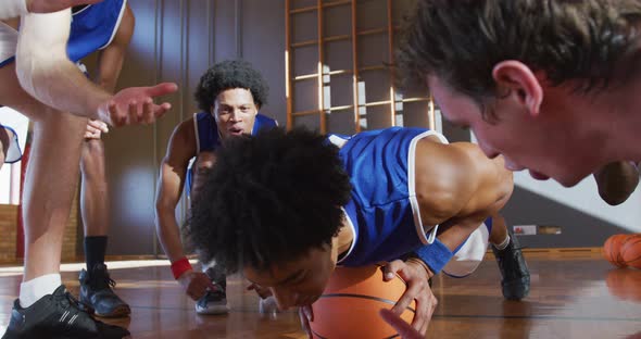 Diverse male basketball team wearing blue sportswear and doing push ups alt
