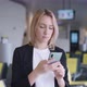 An Attractive Young Woman at the Airport is Texting with Friends on Her Smartphone - VideoHive Item for Sale