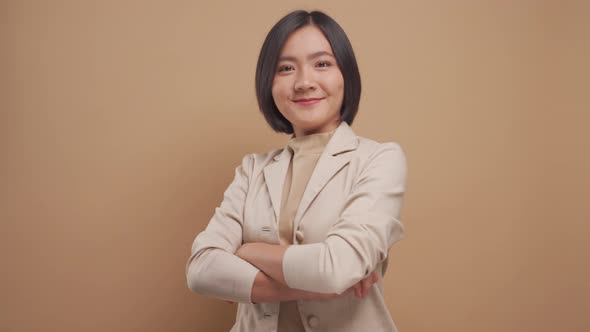 Confident business asian woman happy standing and crossed arms isolated over beige background.