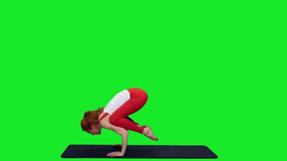 Fit Flexible Woman Doing Bakasana Yoga Pose Against Green Screen
