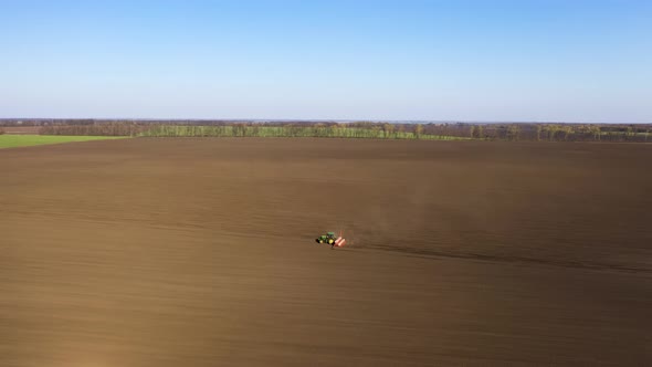 Aerial View Of Tractor Pulling Drill Sowing Seed In Field