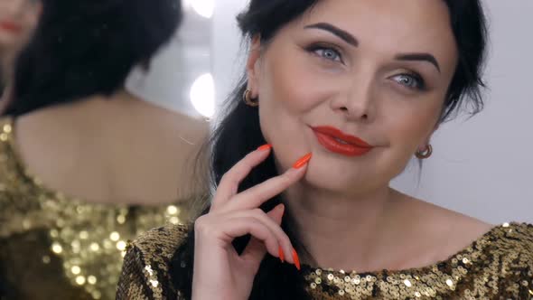 A Beautiful Showy Young Woman with a Stunning Evening Make Up Smoky Eyes in a Sparkling Gold Dress alt