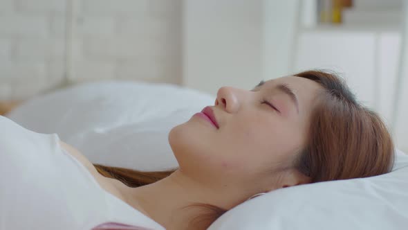 Close up on face Asian young woman close her eyes lying on bed and sleep in cozy bedroom alt