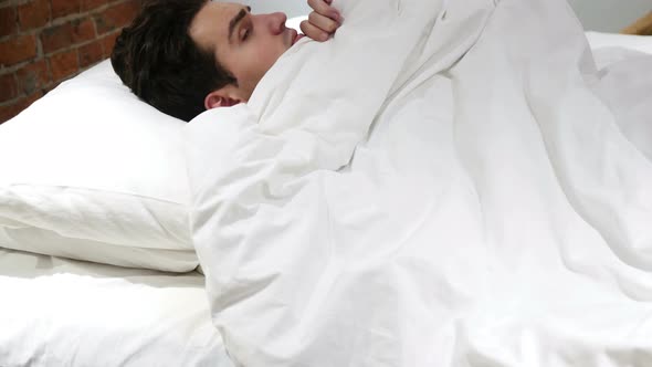 Young Man peeking out from Blanket in bed alt