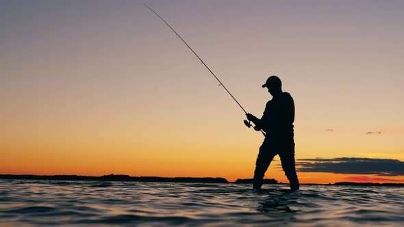 Male Fisher Is Reeling Up a Fishing Pole While Standing in the Water ...