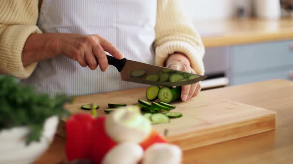 Hands of Woman Chopping Cucumber on Kitchen