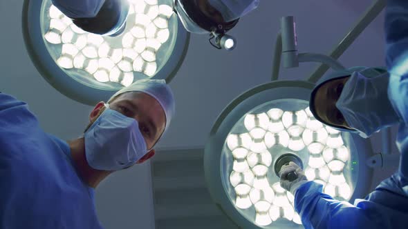 Upward view of Multi-ethnic Surgeons performing surgery in operation theater at hospital alt