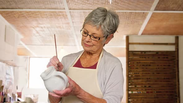 Female potter painting a jug alt