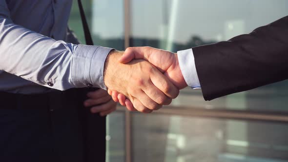 Dolly Shot of Two Businessmen Shaking Hands After Successful Deal Near Office Building. Close Up of alt