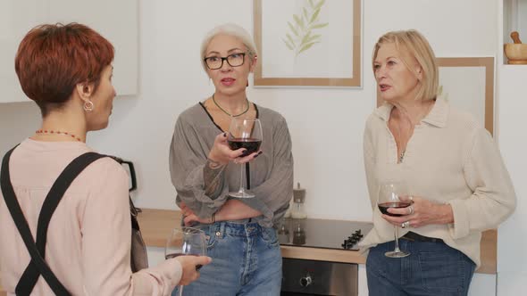 Three Mature Girlfriends Drinking Wine and Chatting at Kitchen alt