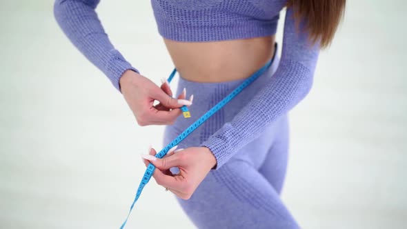 Woman in Trendy Colour Sportswear Holding Tape Measure