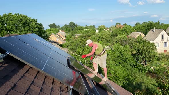 Worker Carefully Steps on Roof to Install New Solar Panels Being Secured with Rope