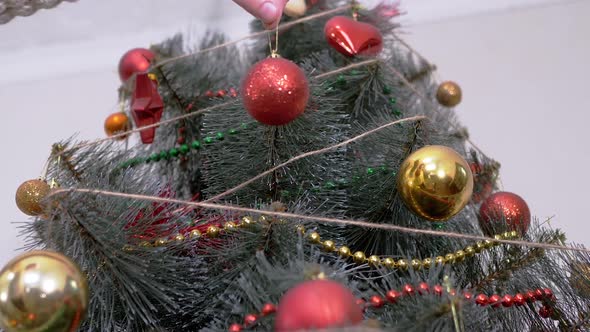 Female Hands Decorate Christmas Tree with New Year Christmas Decorations alt