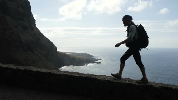 Male Hiker with Backpack Is Walking on the Edge of a Road in Canary Islands alt