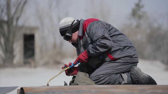 Welder in a Protective Mask and Gloves Welds Metal Column on a Special Table Using a Welding Machine