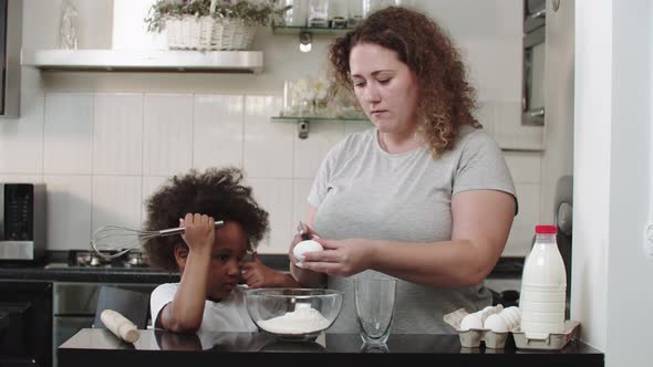 Mixed Family Baking  Mom Breaks an Egg Into a Glass Bowl for the Dough alt