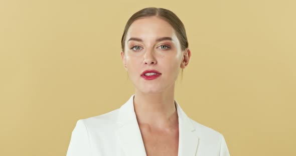 Beautiful Caucasian woman in white blazer posing and looking at camera