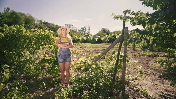 Young woman farmer stands on the plantation. Portrait of a woman gardener in an orchard. alt